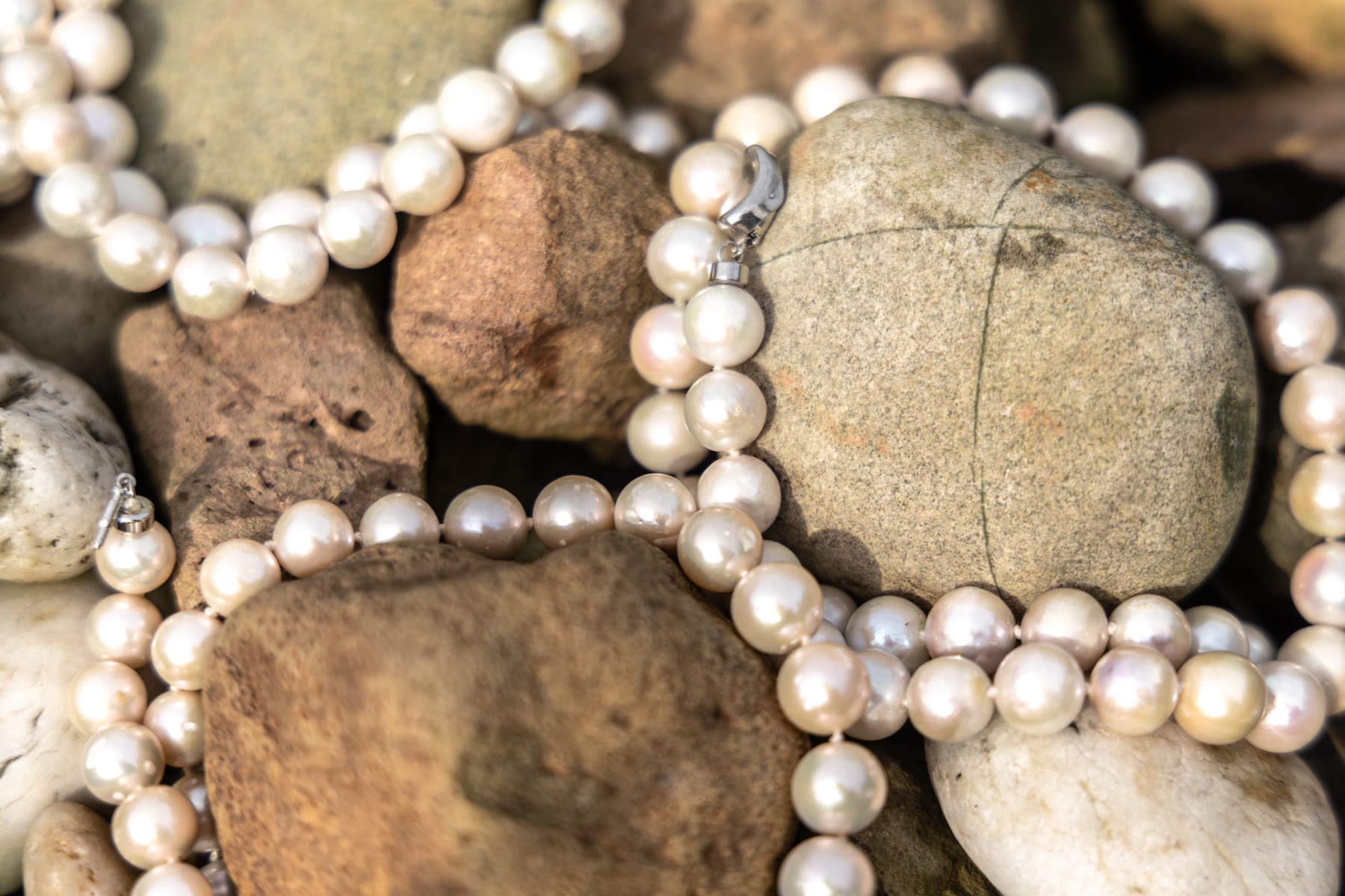 Collier de perles d'eau douce posé sur les galets